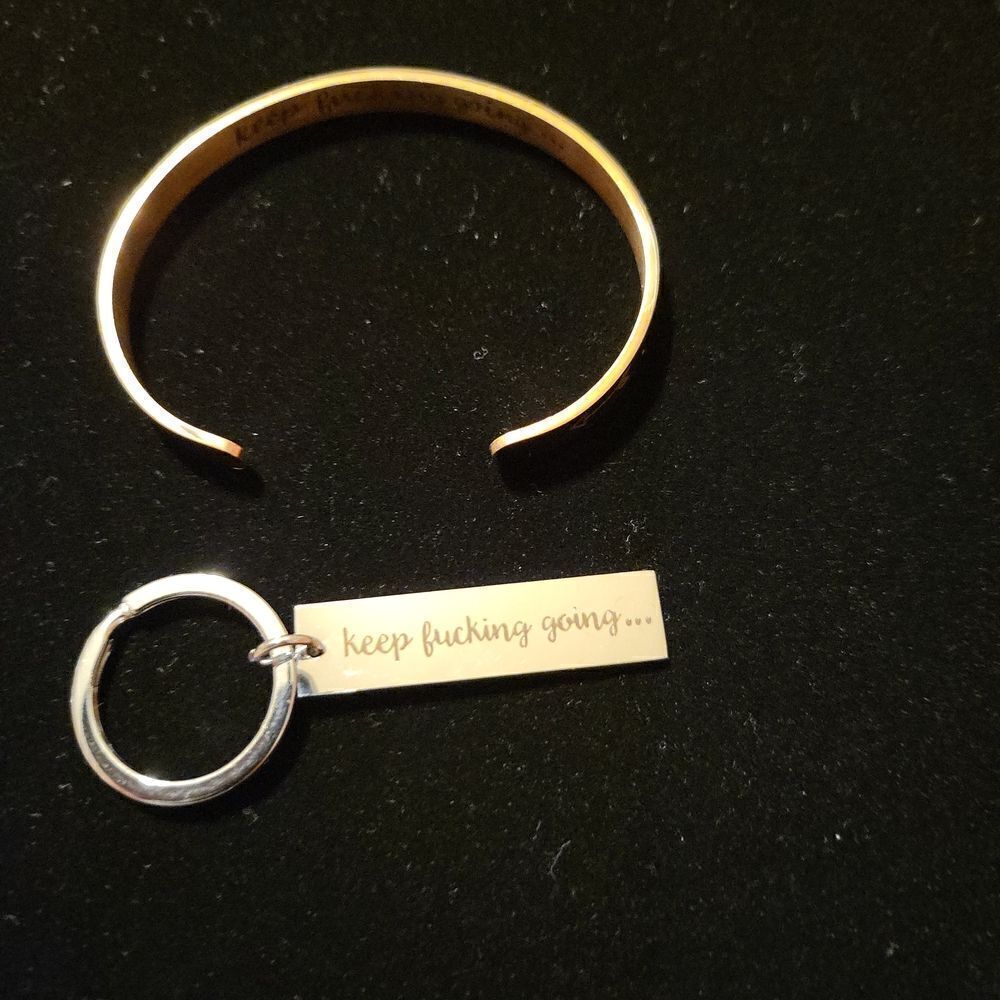 A rose gold cuff bracelet and a silver key chain